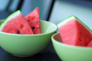 Three red watermelon slices in a mint green bowls