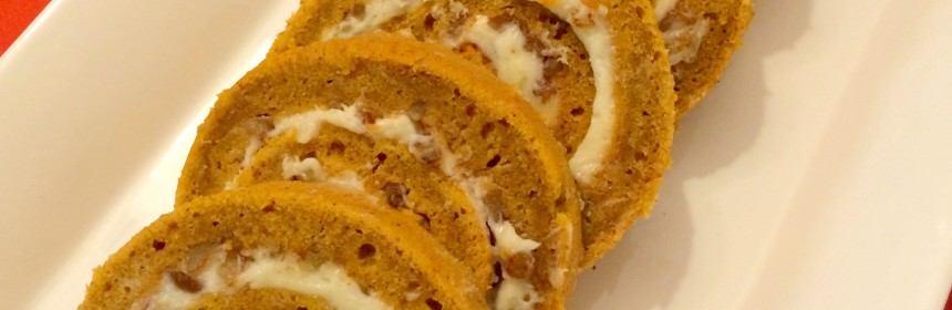 pumpkin roll sliced into pinwheels and arranged in a row in a white platter